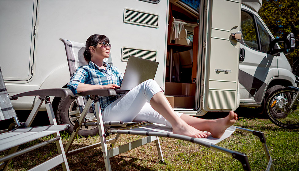 Woman on laptop outside motorhome
